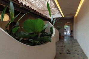 A hallway with a curved wall, a tiled floor, and a ceiling with a patterned design. - Moonlight Homestay & Garden (P. Thong Nhat)