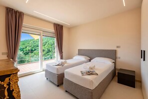 Un dormitorio con dos camas, una mesa de madera y vistas a un paisaje verde a través de amplios ventanales.