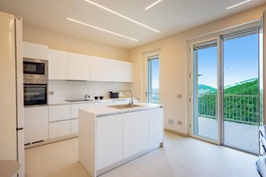 Una cocina moderna con armarios blancos, horno empotrado y una isla grande con un lavamanos.