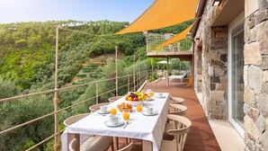 A terrace with a table set for breakfast, overlooking a lush landscape. - Relais Le Torri in Verici (Casarza Ligure)