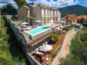 Un hotel con piscina en la azotea, asientos exteriores y un muro de contención de piedra.