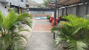 A covered outdoor area with a pool, seating, and a Heineken sign. - The Oak Residence (Abuja)