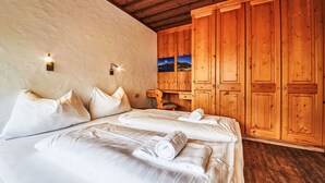 Une chambre avec deux lits, une armoire en bois et une petite table avec une chaise.