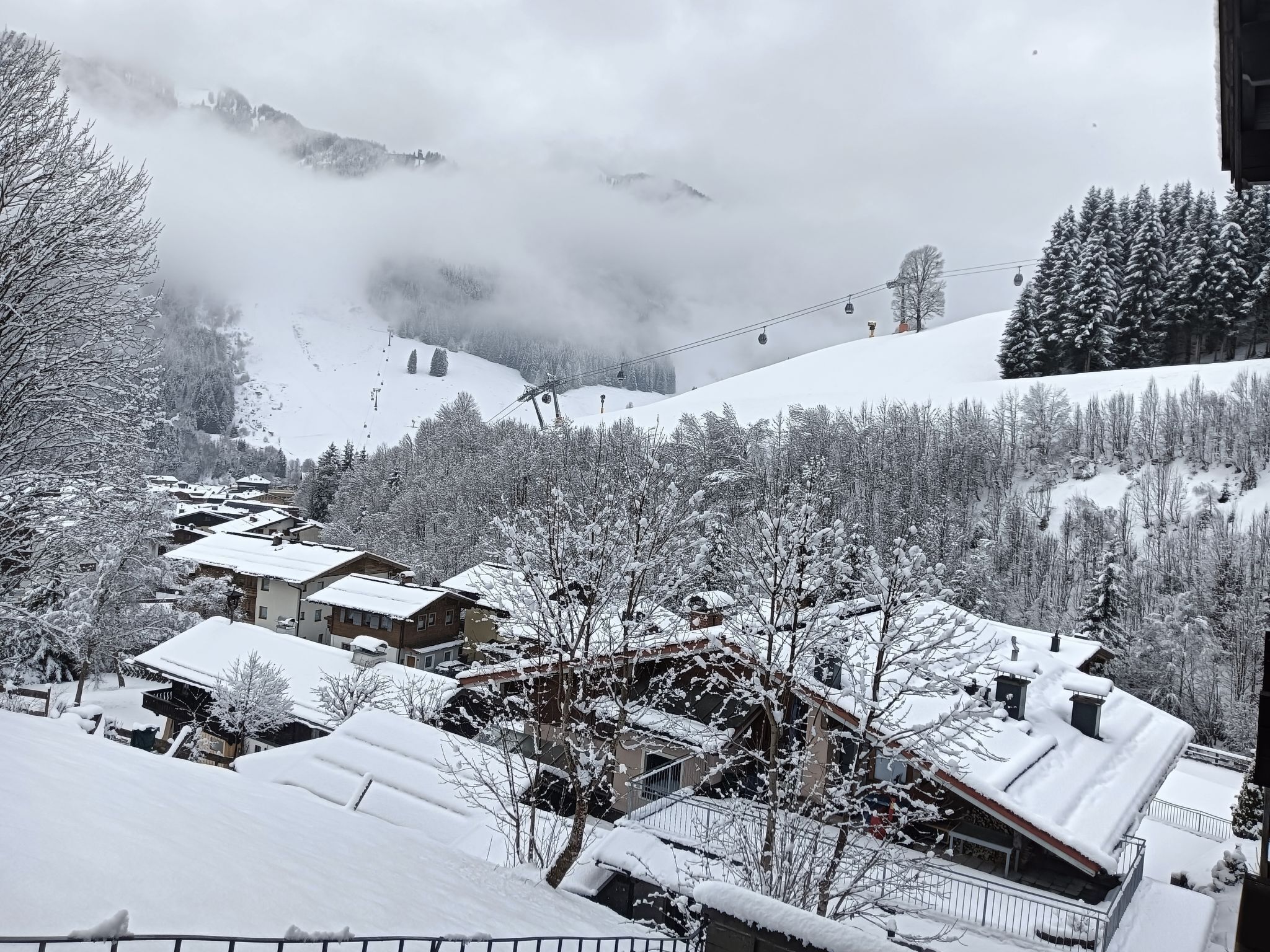 Un village enneigé, avec des maisons, un télésiège et une montagne en toile de fond.