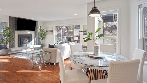 A modern living room with a fireplace, a glass coffee table, and a dining area with white chairs. - Quiet 5BR Bend Retreat - Minutes to Downtown, Trails & More (Bend)