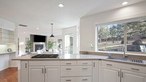 A modern kitchen with white cabinetry, a large island, and a window offering a view of the outdoors. - Quiet 5BR Bend Retreat - Minutes to Downtown, Trails & More (Bend)