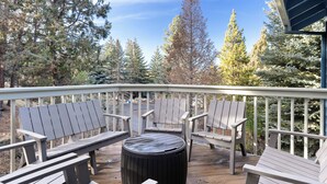 A wooden deck with Adirondack chairs and a round ottoman. - Quiet 5BR Bend Retreat - Minutes to Downtown, Trails & More (Bend)
