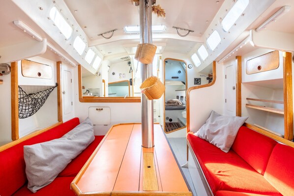 Un espace intérieur compact avec une table centrale, des sièges rouges et un hamac en filet.