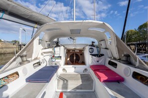 L'intérieur d'un bateau, avec un volant, deux espaces de sièges rembourrés et une table centrale.