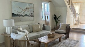 Een woonkamer met een bank, fauteuils, een salontafel, een lamp en een schilderij.