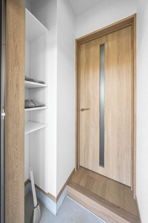 A wooden door with a vertical handle and a small window, leading to a closet with three shelves. - CHARMANT 1A (Minamifurano)