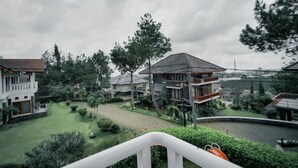 A residential area with multiple houses, a small pond, and a cloudy sky.