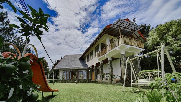 A two-story house with a balcony, a slide, and a garden.