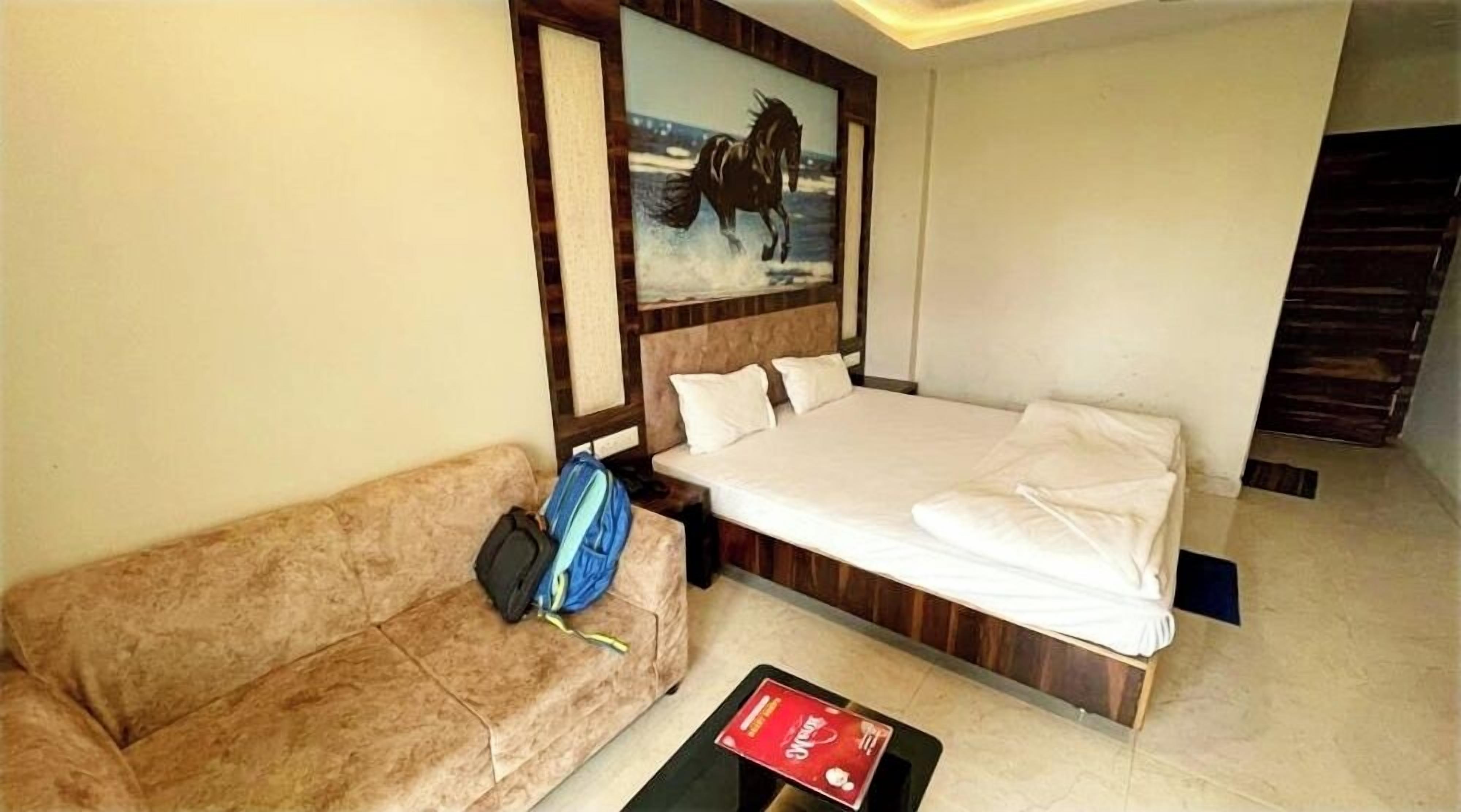 Una habitación de hotel con cama, sofá, un cuadro y una mesa de centro.
