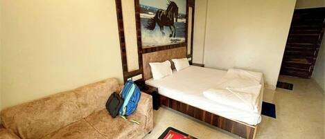 Una habitación de hotel con cama, sofá, un cuadro y una mesa de centro.