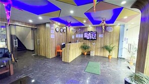 Un'area di accoglienza con una scrivania in legno, un televisore a schermo piatto e una scala che conduce a un piano superiore.