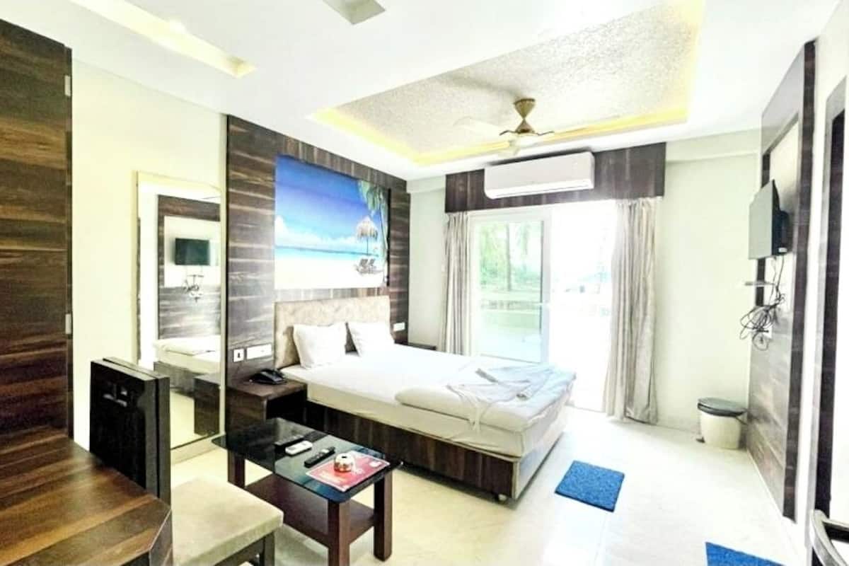 A hotel room with a bed, bedside table, desk, and a large window.