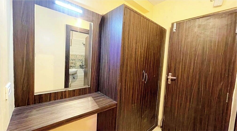 A room with a wooden vanity, a large mirror, and a wardrobe.