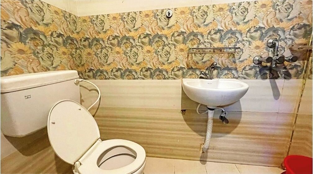 A bathroom with a toilet, sink, and floral-patterned walls.