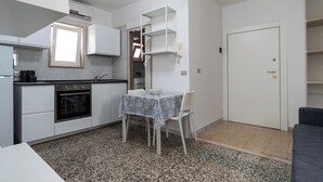 A compact kitchen with a dining table, white cabinets, and a built-in oven. - Casina del Parco by Wonderful Italy (Bari)
