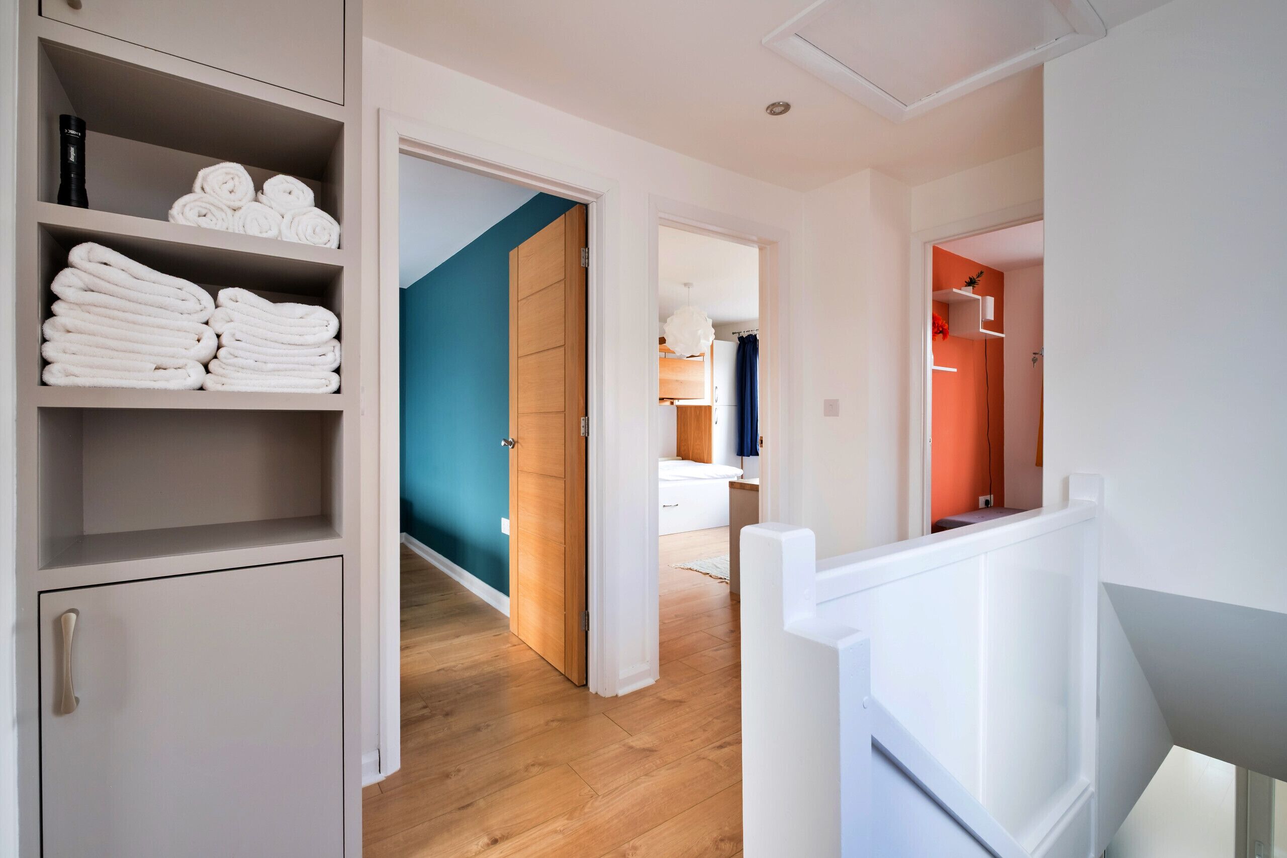 A hallway with a wardrobe, a staircase, and a view into a bedroom.