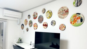 Ein modernes Wohnzimmer mit einem an einer weißen Wand befestigten Flachbildfernseher, umgeben von verschiedenen runden Wandbildern.