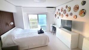 Ein Hotelzimmer mit Bett, Fernseher, Schreibtisch und einem Balkon mit Blick.