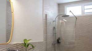 A modern bathroom with a wooden vanity, a white sink, a mirror with a gold frame, a small plant, a shower with a glass door, and a toilet. - A modern, well-equipped bungalow with an exceptional view of the lagoon! (Bora-Bora)