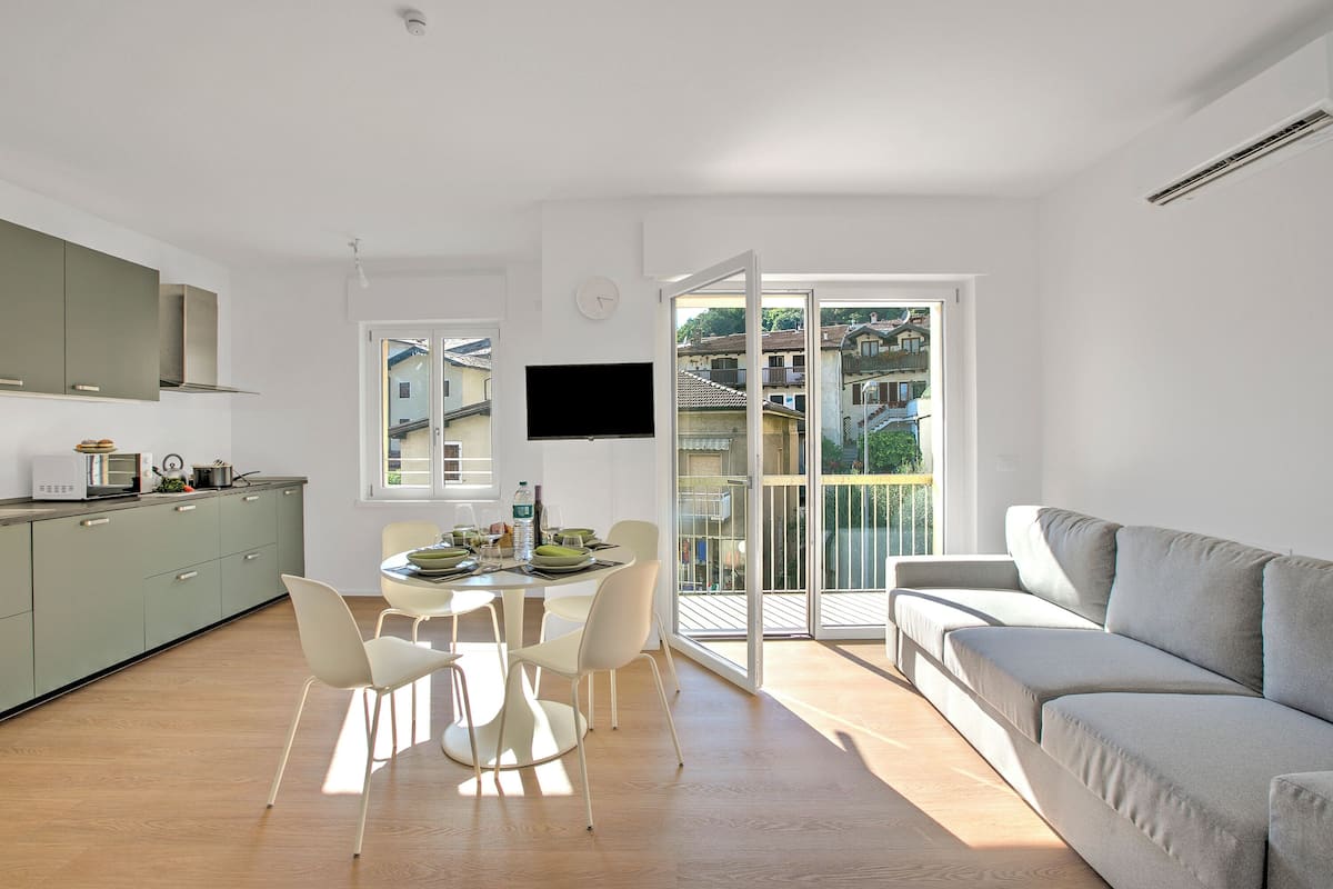 Ein moderner Wohnraum mit Küche, Essbereich und einem Balkon mit Blick auf die Stadt.