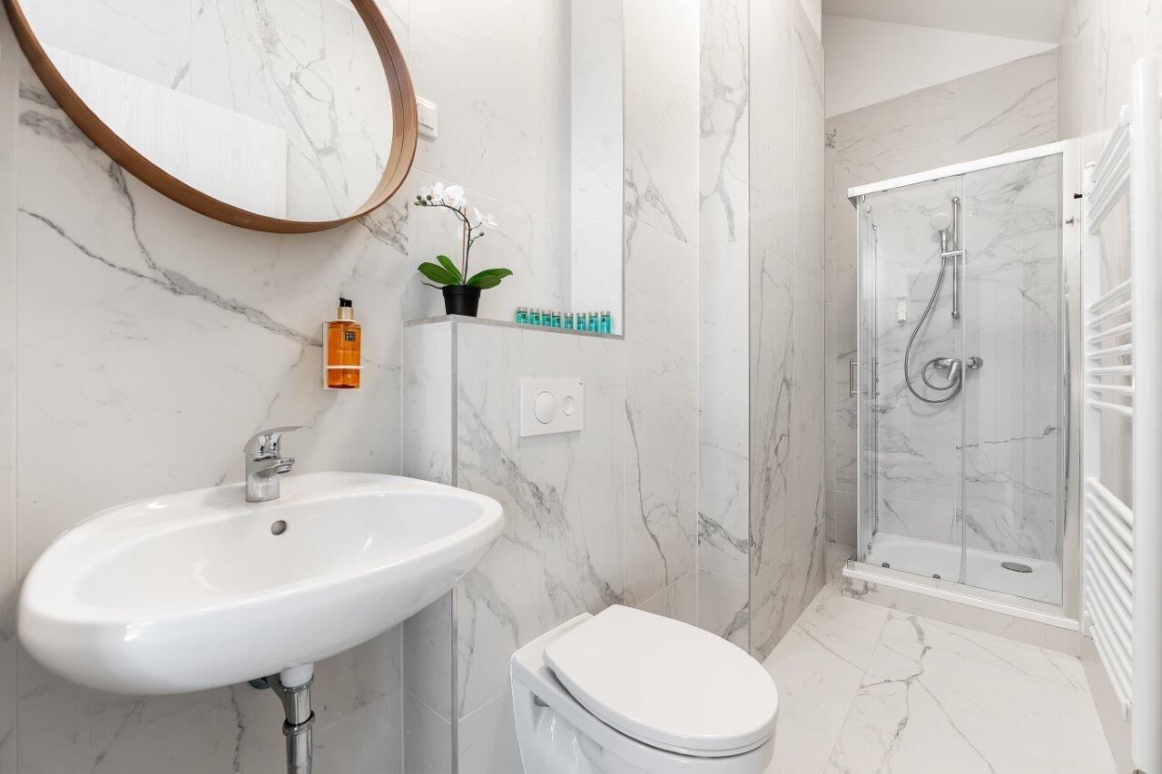 Un baño con lavamanos blanco, inodoro y cabina de ducha con paredes de vidrio.