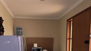 Eine kleine Küche mit Kühlschrank, Mikrowelle und einer kompakten Arbeitsfläche.