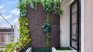 A narrow balcony with a vertical garden, a small planter with green plants, and a window with a black frame. - Quattrick Villa (Batu Sub-District)