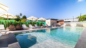 A swimming pool with lounge chairs and umbrellas, surrounded by greenery and a clear sky. - Phuket Five Fortune Holiday Hotel (Rawai)