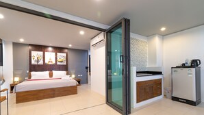 A modern hotel room with a bed, bedside table, lamp, and a refrigerator. - Phuket Five Fortune Holiday Hotel (Rawai)