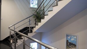 En moderne trappe med gelændere i metal og glas, der fører op til en etage.