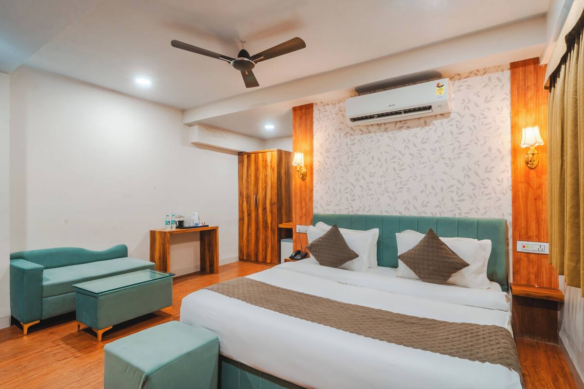 A hotel room with a bed, a desk, a chair, a ceiling fan, and an air conditioning unit.