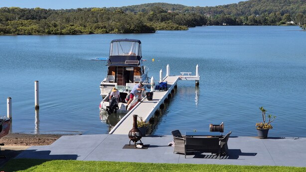 A docked boat with a covered seating area and a small table, surrounded by a grassy area and a potted plant. - Direct water front 3 meters from Lake.
Your own private balcony overlooking Lake (Fennell Bay)