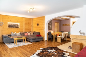 A cozy room with a wooden floor, a sofa, a dining table, and a fireplace.