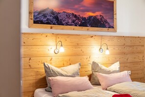 Un dormitorio con paneles de madera, una cama con almohadas y un cuadro enmarcado de montañas.