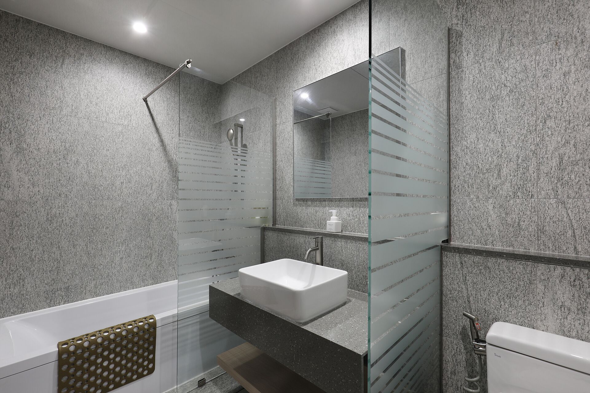 A modern bathroom with a glass shower enclosure, a white sink, and a toilet.