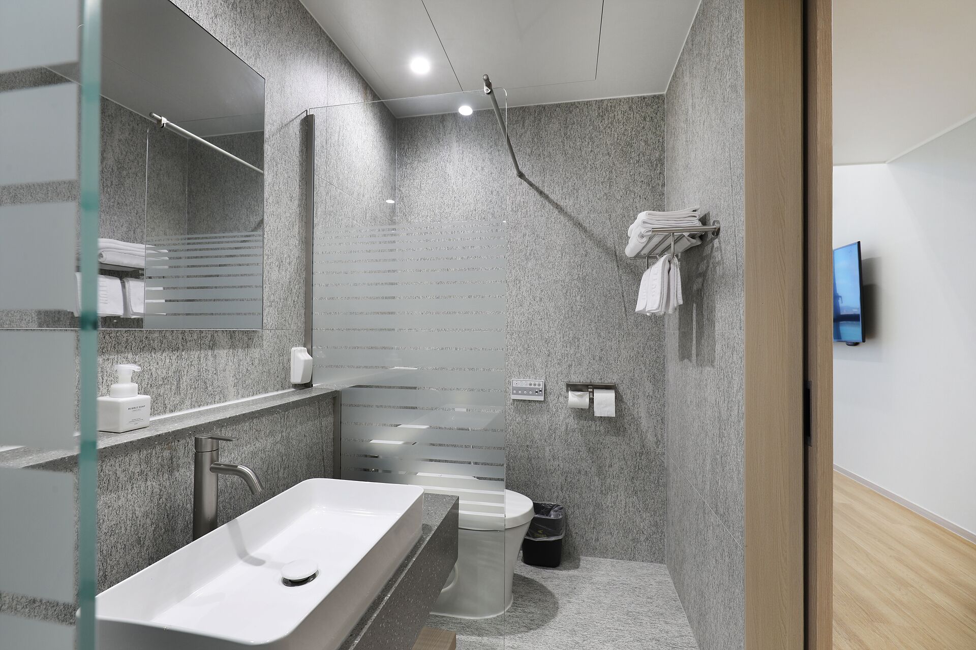 A modern bathroom with a rectangular sink, a toilet, and a shower area.