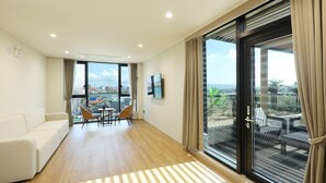 A modern living room with a sofa, chairs, a small table, and a TV. - Pohang Hound Hotel Songdo Beach (Pohang)