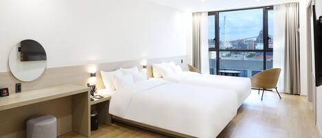 Et moderne hotelværelse med en stor seng, sengeborde, et rundt spejl og udsigt over byen gennem store vinduer.