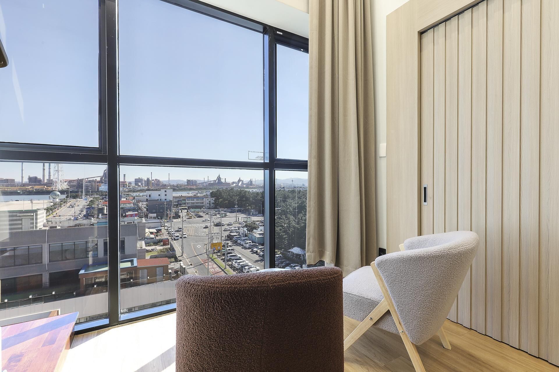 Habitació moderna amb una finestra gran, vista a la ciutat i dues cadires.