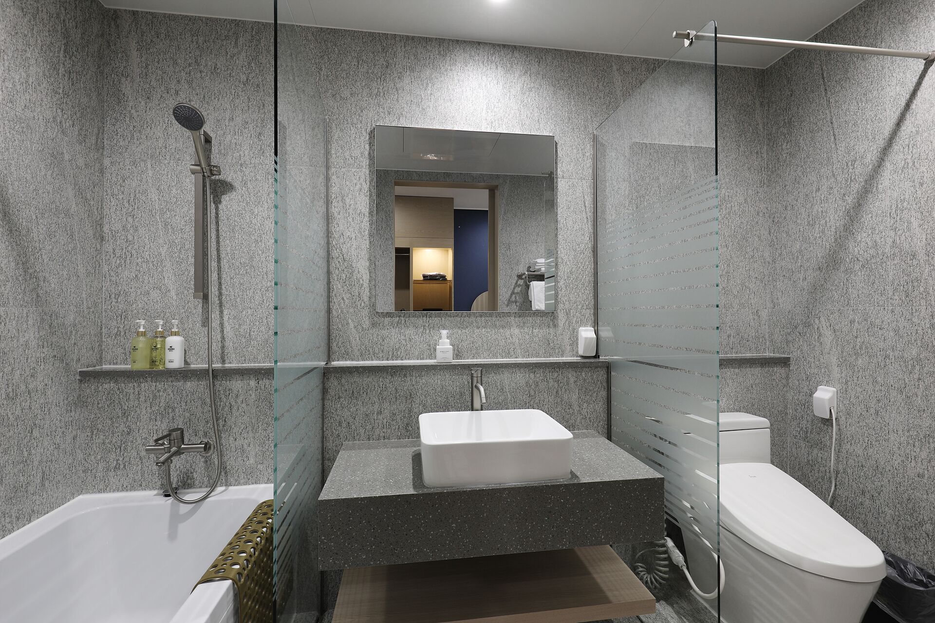 Een moderne badkamer met een vrijstaand bad, een douche met glazen wanden, een wastafelmeubel met wastafel en een toilet.