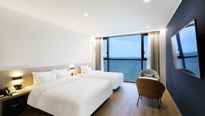 A modern hotel room with two beds, a desk, a chair, and a large window offering a sea view. - Pohang Hound Hotel Songdo Beach (Pohang)