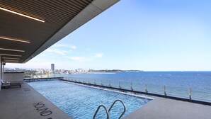An infinity pool with a city view, a lounge area, and a deck with a railing overlooking the water. - Pohang Hound Hotel Songdo Beach (Pohang)