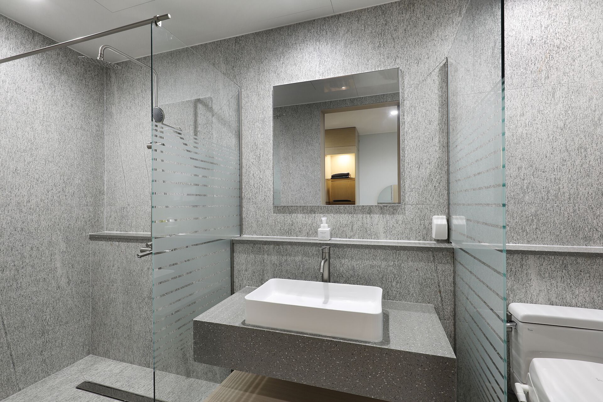 Un baño moderno con cabina de ducha de vidrio, un lavabo blanco y un espejo grande.