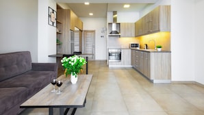 Una cocina moderna con armarios de madera, una zona de comedor con sofá y mesa, y una planta pequeña sobre la mesa.