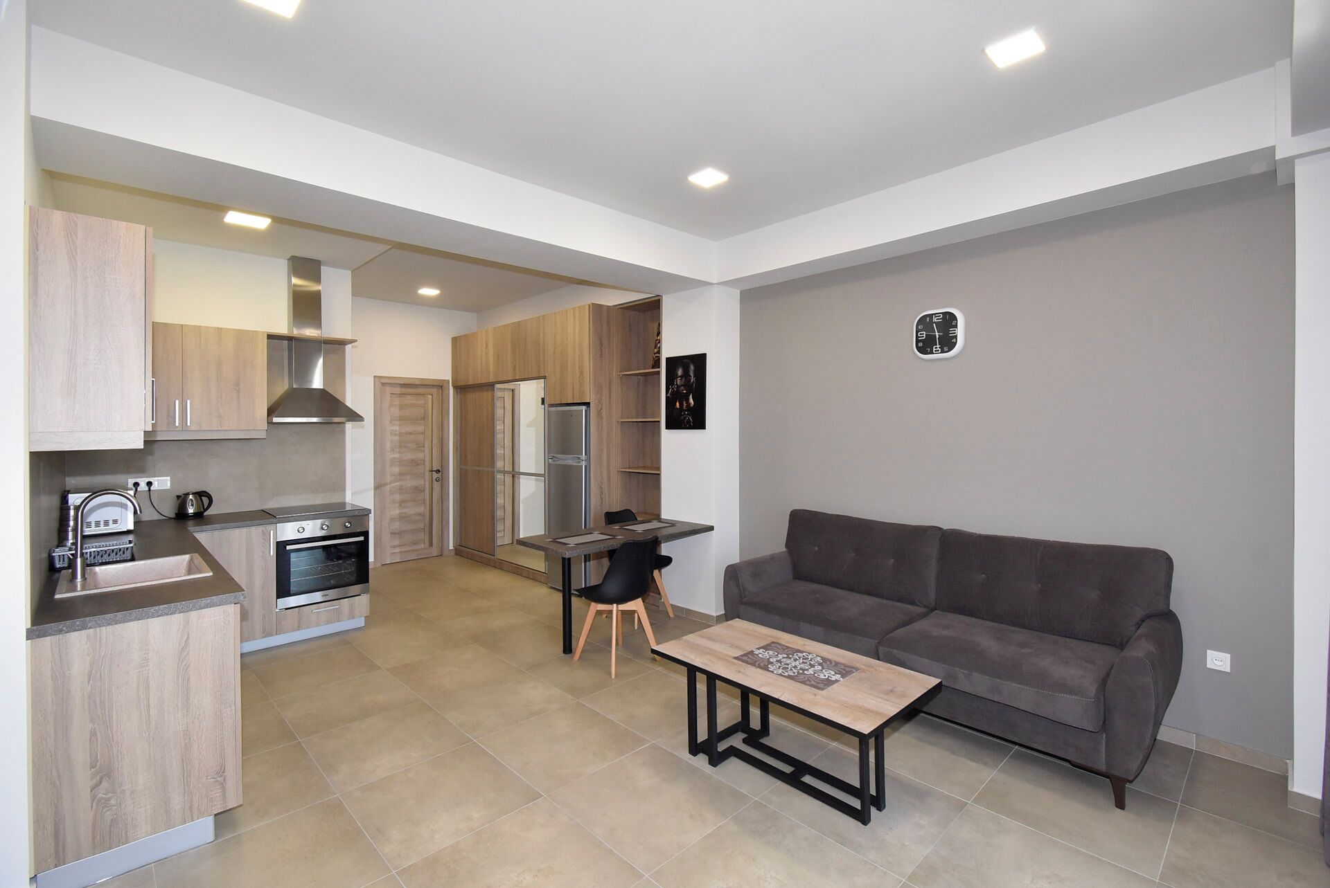 A modern apartment with a kitchenette, a dining area, and a living room with a sofa and coffee table.